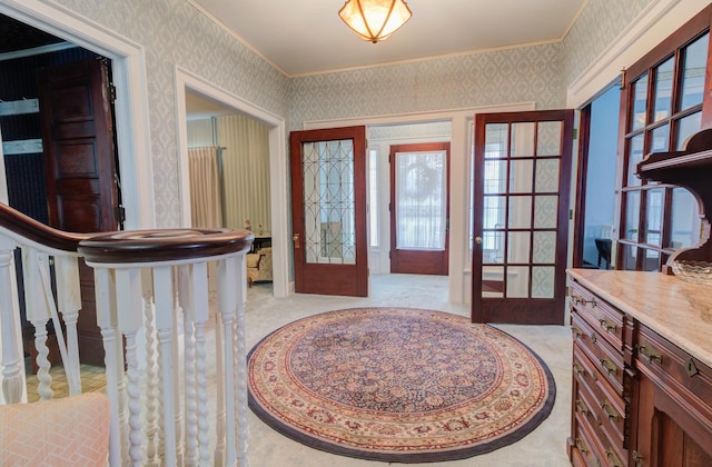 entrance foyer featuring ornamental molding, french doors, light colored carpet, and wallpapered walls