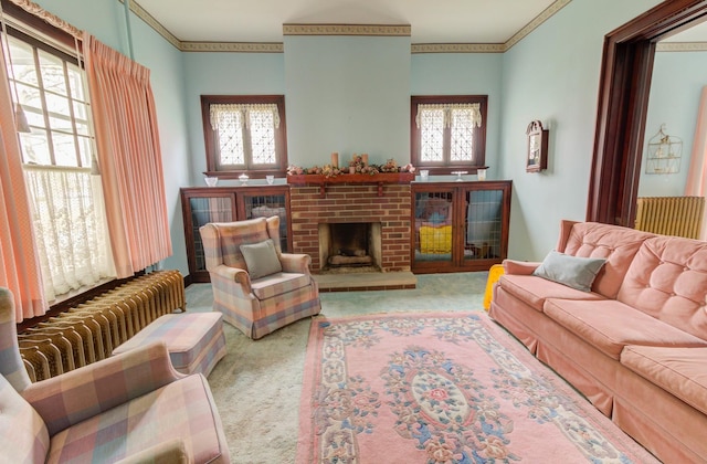 carpeted living area featuring a brick fireplace, radiator, and crown molding