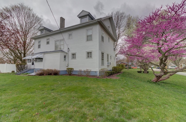 rear view of property with a yard, a chimney, and fence