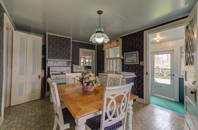 dining room featuring ornamental molding, baseboards, and wallpapered walls