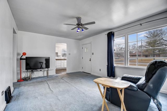 living area featuring carpet floors, baseboards, and a ceiling fan