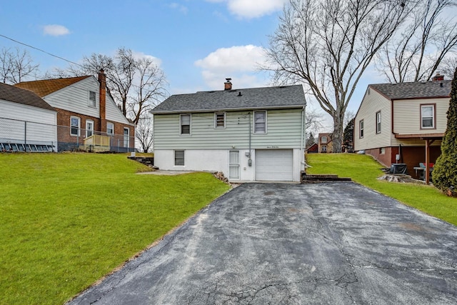 view of front of house featuring aphalt driveway, a front yard, a chimney, and a garage