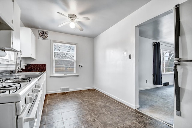 kitchen with baseboards, freestanding refrigerator, visible vents, and white cabinetry