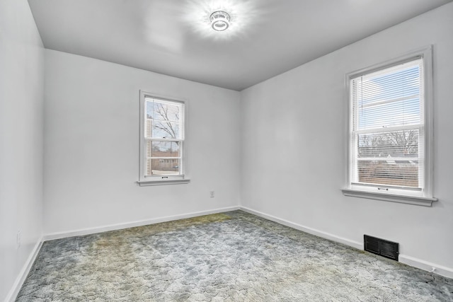 carpeted spare room with visible vents and baseboards