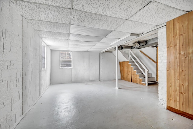 basement with a paneled ceiling and stairway