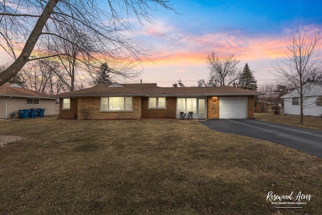 ranch-style house featuring driveway, brick siding, a garage, and a front yard