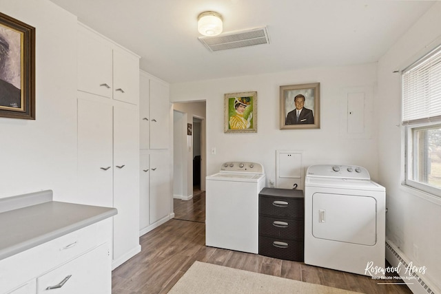 washroom featuring separate washer and dryer, wood finished floors, visible vents, baseboard heating, and cabinet space