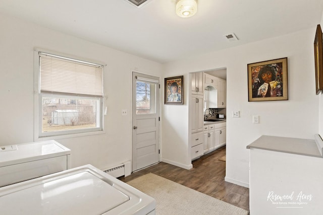 clothes washing area featuring dark wood-style flooring, visible vents, washing machine and dryer, a sink, and laundry area