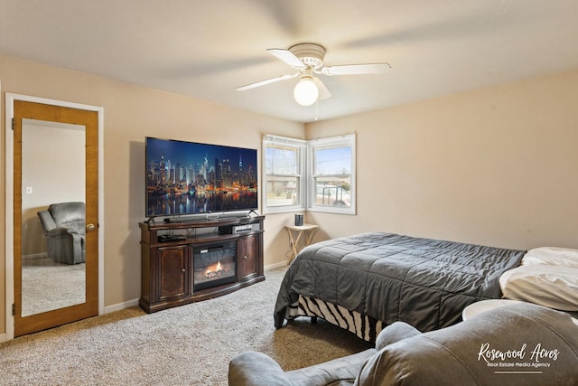 carpeted bedroom with ceiling fan, baseboards, and a glass covered fireplace