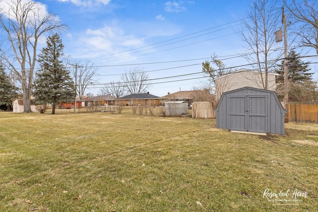 view of yard featuring an outbuilding, fence, and a shed