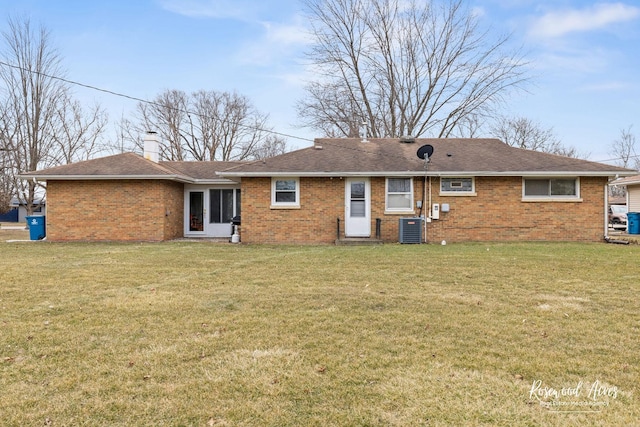 back of house with central AC unit, a lawn, and brick siding