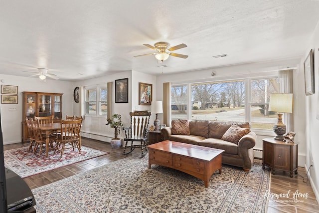 living room featuring wood finish floors, a textured ceiling, baseboards, and a baseboard radiator