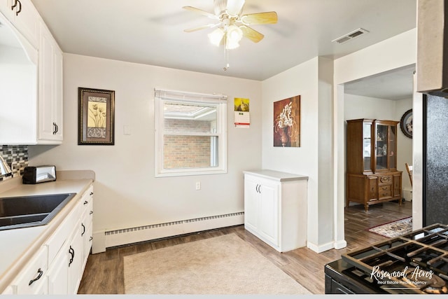 kitchen featuring light wood-style floors, visible vents, a baseboard heating unit, and a sink