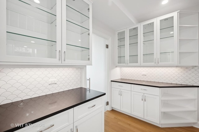 kitchen featuring glass insert cabinets, dark countertops, white cabinets, and open shelves