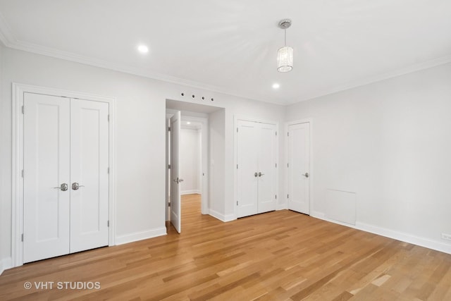 unfurnished bedroom with baseboards, ornamental molding, light wood-style floors, two closets, and recessed lighting