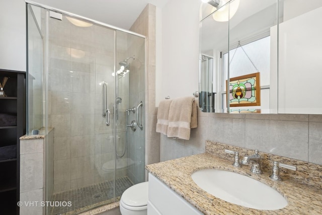 full bathroom with toilet, a shower stall, decorative backsplash, and vanity