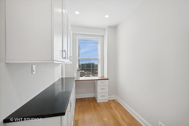 home office featuring light wood finished floors, recessed lighting, built in study area, and baseboards