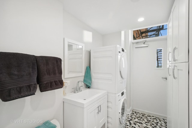 laundry area with stacked washing maching and dryer, a sink, and cabinet space