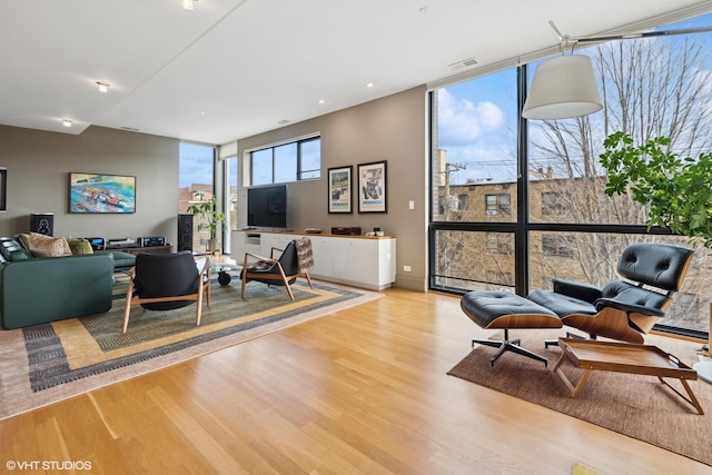 living room with expansive windows, wood finished floors, and visible vents