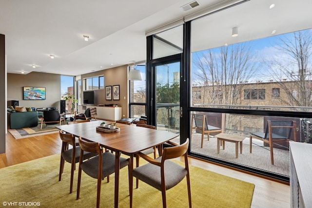 dining area featuring a wall of windows, visible vents, and wood finished floors