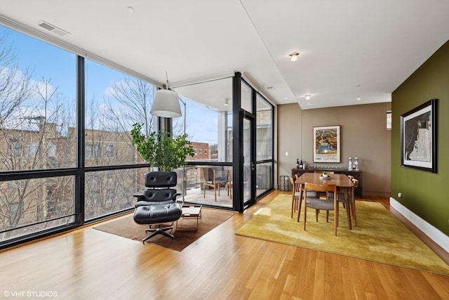 dining room with expansive windows, wood finished floors, visible vents, and baseboards