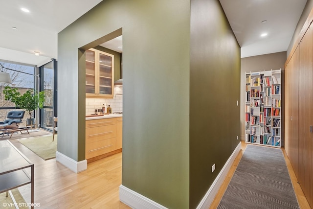 corridor featuring recessed lighting, light wood-type flooring, and baseboards