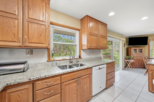 kitchen featuring light stone countertops, decorative backsplash, a sink, and dishwasher