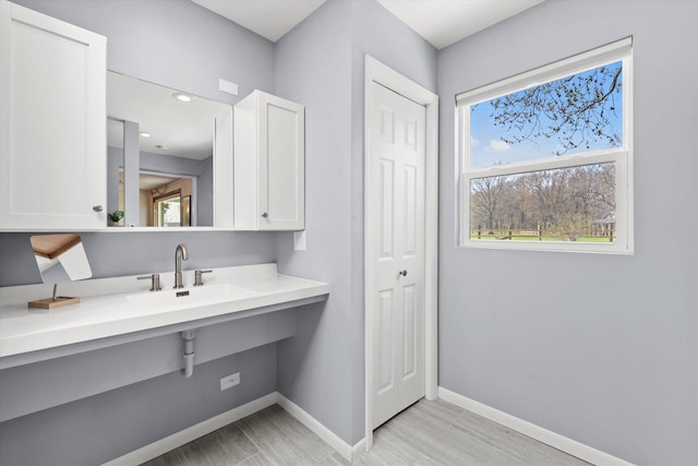 bathroom featuring baseboards, a sink, and wood finished floors