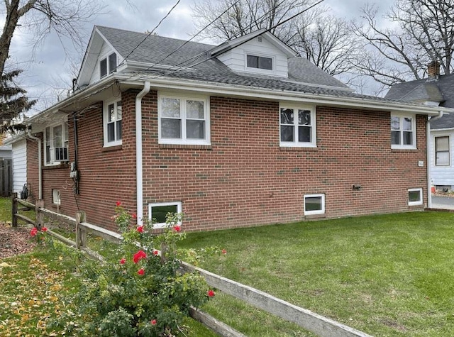 view of side of home featuring a yard, brick siding, and roof with shingles