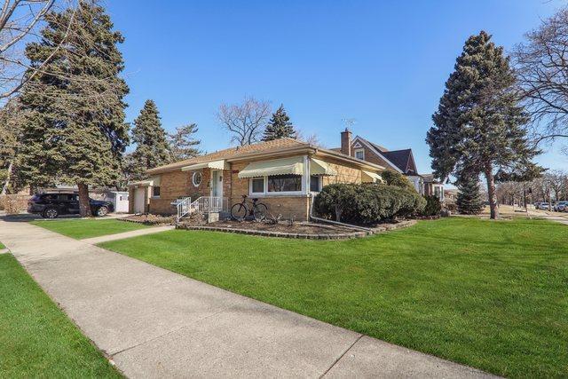 view of front of home with brick siding, a chimney, and a front yard