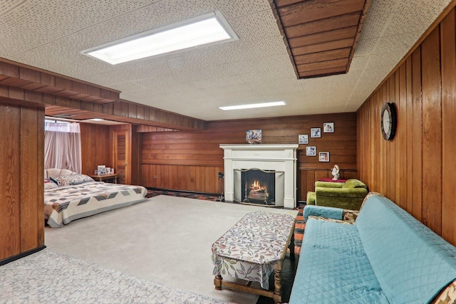 carpeted bedroom with a lit fireplace and wooden walls