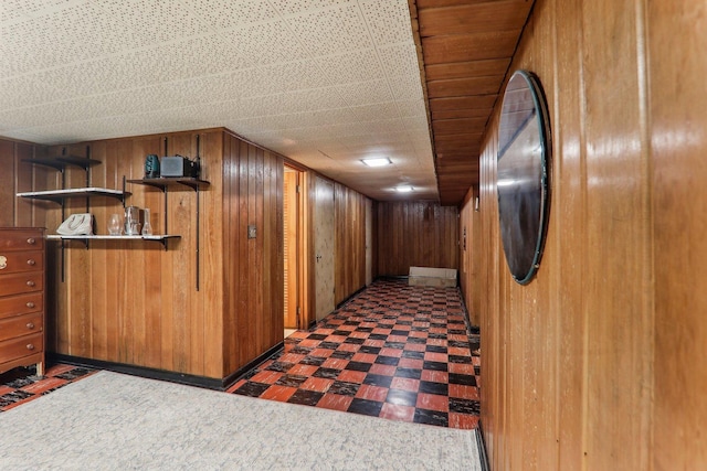 hall featuring tile patterned floors and wooden walls