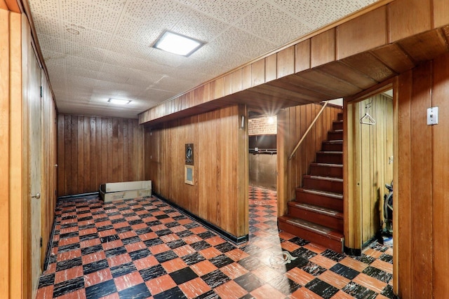 finished below grade area with stairway, wood walls, and tile patterned floors