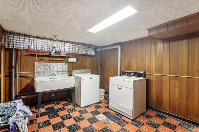 laundry room with washing machine and dryer, a sink, wooden walls, laundry area, and tile patterned floors