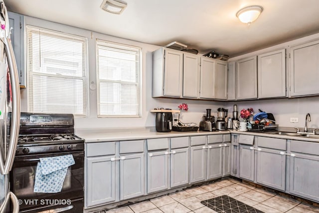 kitchen with gray cabinets, light countertops, visible vents, gas stove, and a sink