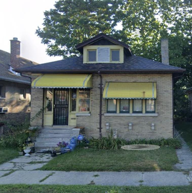 bungalow-style house with a chimney and brick siding