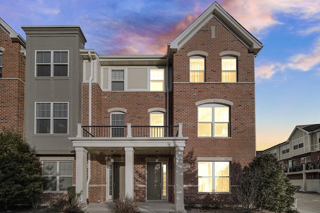 view of property featuring brick siding and a balcony