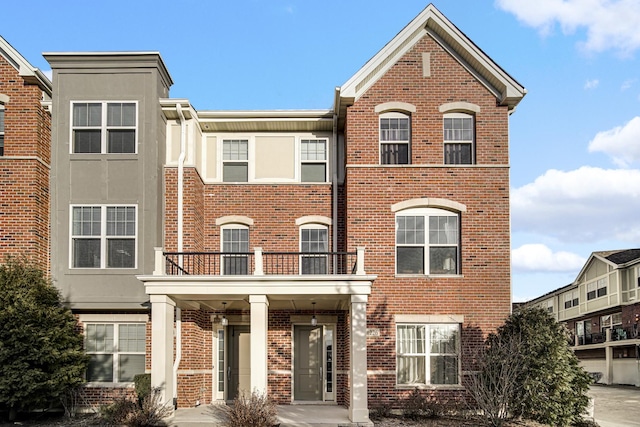 townhome / multi-family property with brick siding and a balcony