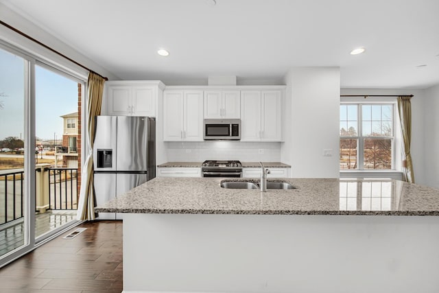 kitchen with visible vents, a sink, stainless steel appliances, white cabinetry, and backsplash