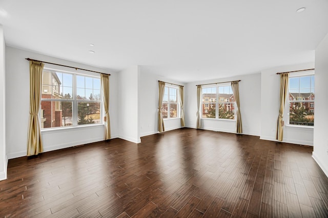 spare room featuring dark wood-type flooring and baseboards