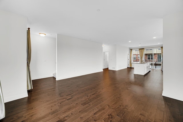 unfurnished living room with baseboards, dark wood finished floors, and recessed lighting