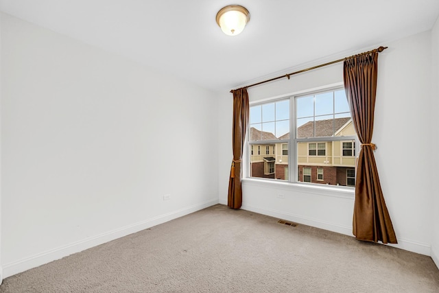 carpeted spare room featuring visible vents and baseboards