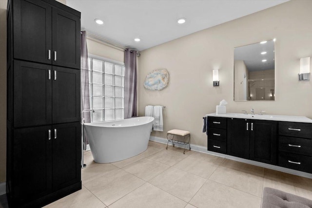 full bath with recessed lighting, a freestanding bath, vanity, baseboards, and tile patterned floors