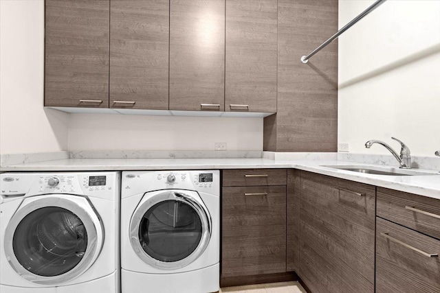 washroom featuring cabinet space, a sink, and washing machine and clothes dryer