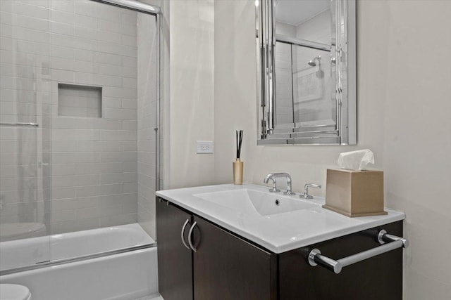 bathroom featuring toilet, bath / shower combo with glass door, and vanity