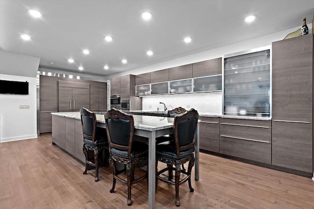 kitchen with a breakfast bar, light wood finished floors, a spacious island, recessed lighting, and modern cabinets