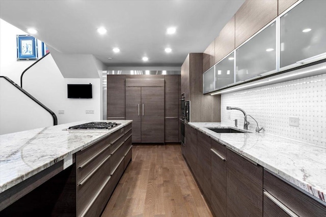 kitchen with a sink, paneled refrigerator, dark brown cabinetry, and modern cabinets