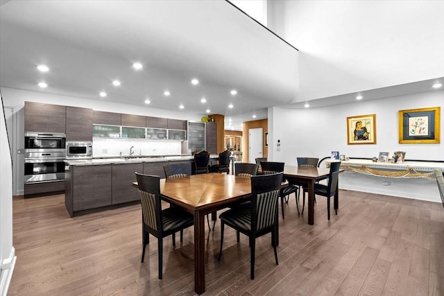 dining room with wood finished floors, a towering ceiling, and recessed lighting