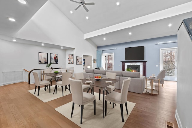 dining room featuring light wood-type flooring, a healthy amount of sunlight, visible vents, and a glass covered fireplace