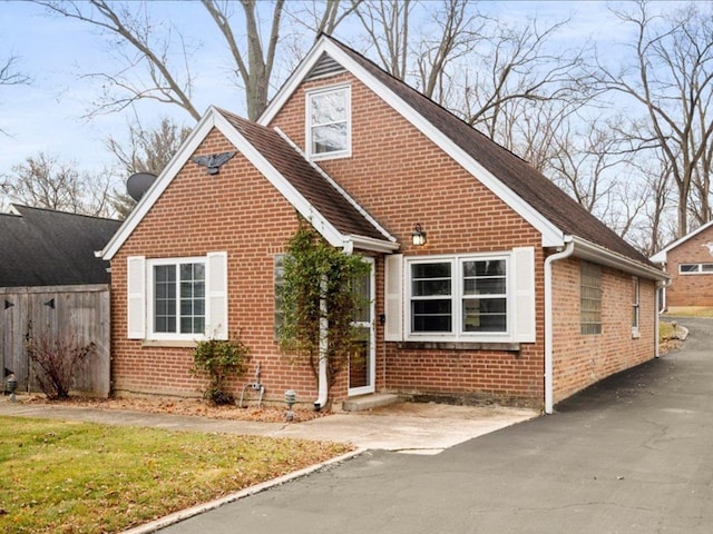 view of front facade featuring brick siding and fence